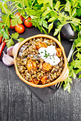 Lentils with eggplant and tomatoes in bowl on board top