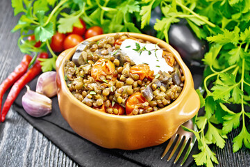 Lentils with eggplant and tomatoes in bowl on dark board