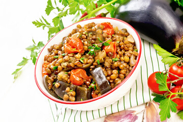 Lentils with eggplant in bowl on board