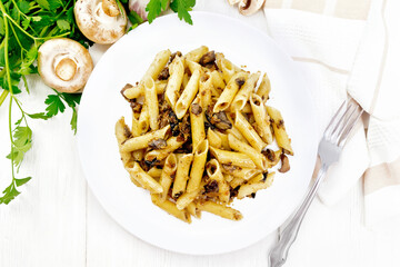 Pasta with mushrooms in white plate on board top