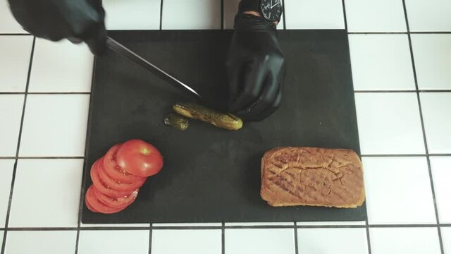 Slicing A Juicy Lightly Salted Cucumber On A Black Cutting Board In A Diner. Chef Ably Slices Vegetables.