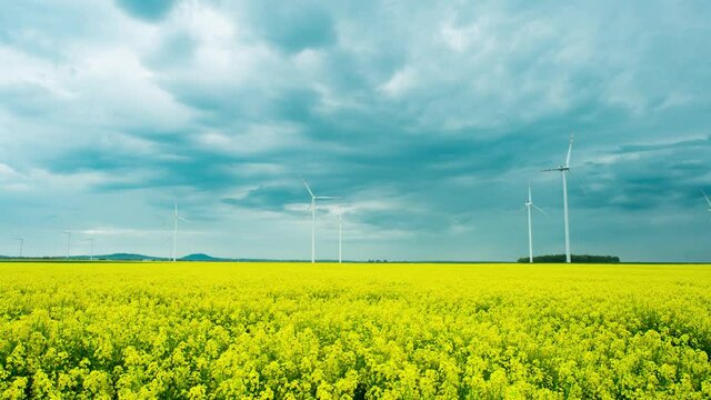Dark clouds moving over windmills and bright green farmlands in Zlotoryja, Poland - time lapse