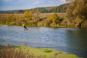 A man crosses the river on ropes stretched from shore to shore. Crossing the river.