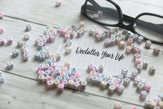 Selective focus of glasses,alphabet beads and paper written  with Declutter Your Life on white wooden background.