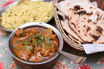 Butter chicken a hot and spicy curry dish marinated in a savory mixture of Rajasthani spices,  garnished with fresh coriander leaves with pulao and roti Jaipur Rajasthan India. North Indian cuisine 