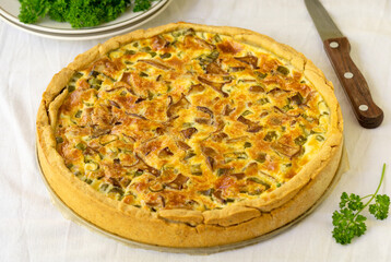 Quiche with chanterelles, herbs and cheese on a white background