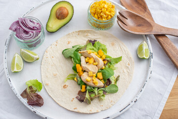 Fresh tortilla wraps with chicken, mushrooms and fresh vegetables on wooden board