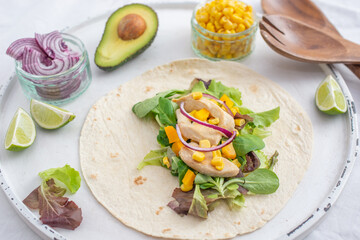 Fresh tortilla wraps with chicken, mushrooms and fresh vegetables on wooden board