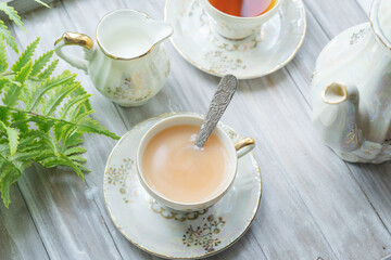 Traditional five o'clock English tea in an elegant china set. Two cups of tea and milk on a wooden vintage tray. Top view.