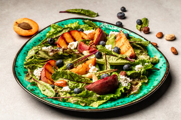 Healthy food concept, Diet salad plate grilled peach salad with goat cheese, blueberry, nuts, overhead view, copy space