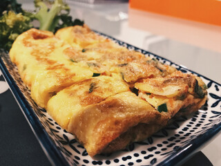 Home made korean egg roll with broccoli in a plate with blue and white pattern design