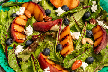 Grilled peach salad with goat cheese, blueberry, nuts on concrete background, Food recipe background. Close up