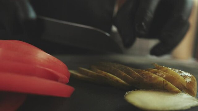 Slicing A Lightly Salted Cucumber On A Black Cutting Board In A Diner. Chef Ably Slices Vegetables.