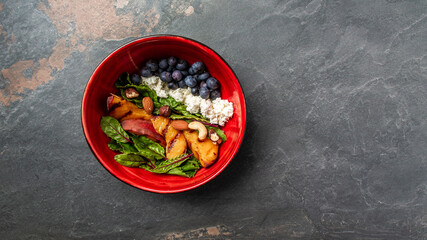 Fototapeta na wymiar Healthy vegetarian salad. Summer peach salad with goat cheese, nuts and blueberry. healthy vegetarian lunch bowl. Long banner format, top view