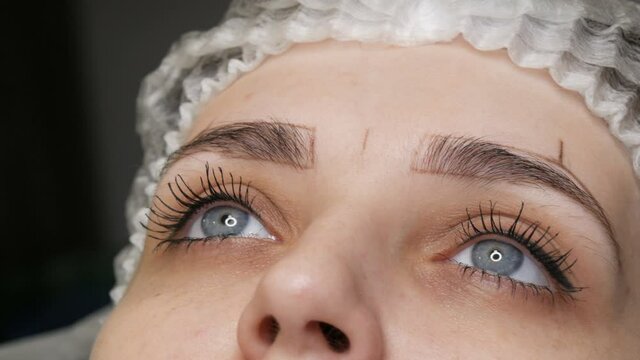 The microblading master corrects the new shape of the eyebrows with a special pencil. Eyebrow Tattoo, Permanent Makeup.