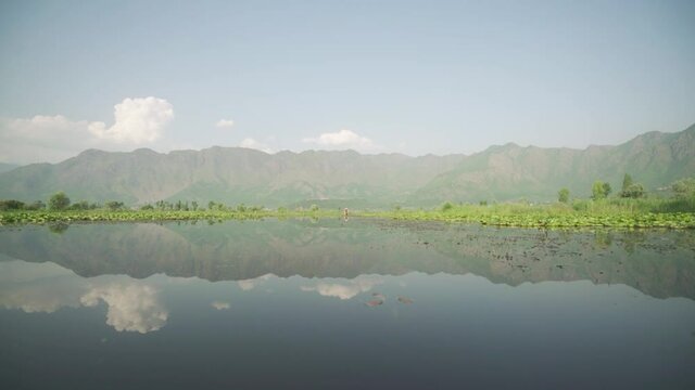 Dal Lake With Mountain And Sky Reflection On The Water On A Beautiful Day In Kashmir, India. View From A Sailing Shikara Boat  - wide shot