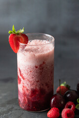 Gradient berries smoothie made with blended cherry, strawberry and raspberry in glass on dark concrete background. Close up of detail