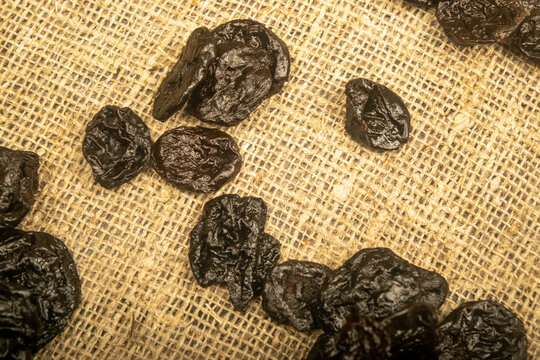 Dried prunes in bulk on burlap with a rough texture. Close up.