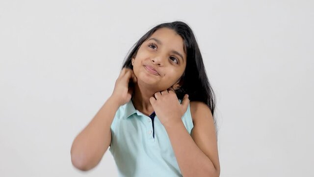 Attractive young girl in casual clothing scratching and rubbing her itchy neck. A cute little kid scrabbling rashy and dry skin around her neck during the summer season - skin issues concept