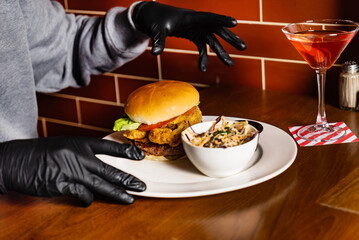 man in black gloves eating burger in the restaurant