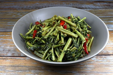 Stir and fried spicy water mimosa with red chilly and garlic seasoning with pepper and fish sauce on the bowl. Famous side dish with porridge in Thailand street food. 