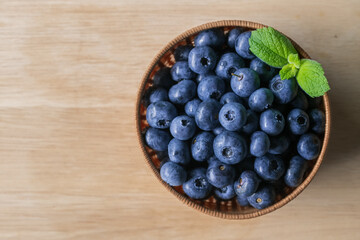 Fresh ripe blueberries in basket on wooden background.

