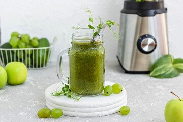 Green vitamin smoothie with shoots of young peas. Green smoothie made from apple, grape and kiwi
