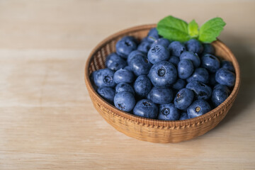 Fresh ripe blueberries in basket on wooden background.
