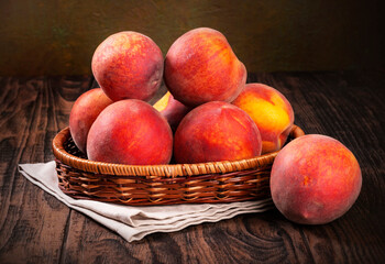 Fototapeta na wymiar Fresh peaches in a basket on a brown wooden table