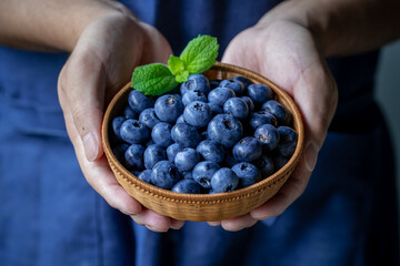 Man holds a wicker basket of blueberries.
