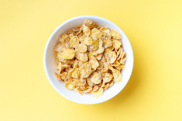 Plate with breakfast cereal on yellow background, view from above