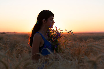 Silhouette of a girl on a background of sunset in an open field