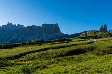 Lastoni de Formin, aka Ponta Lastoi de Formin. Giant mountain block with green meadow, trees and summer sky, Dolomites, Italy.