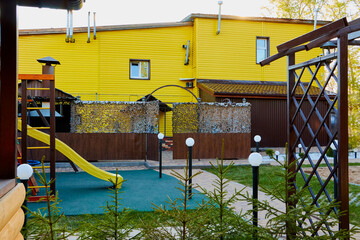 Wooden gazebo on the yard with greenery in a summer day.