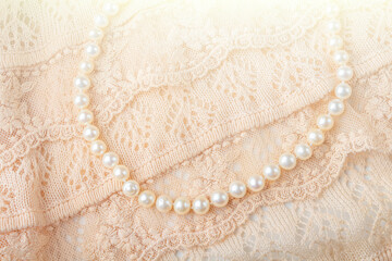 Wedding background. Vintage pearl jewelry necklace on delicate ivory-colored lace cloth. Elegant gift for woman.