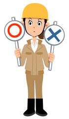 マルとバツの札を両手に持ち考えるヘルメットを被った作業着の女性
