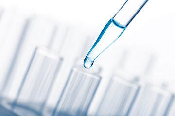pipette with a drop and scientific laboratory test tubes in a research laboratory.