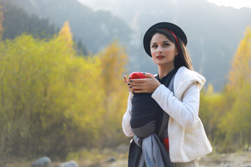 Beautiful young mother with her infant baby in sling outdoor. Babywearing concept