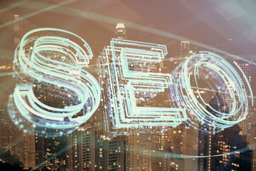 SEO hologram on city view with skyscrapers background double exposure. Search optimization concept.