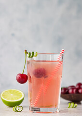 Lemonade or non-alcohol cocktail with cherry and lime in glass on grey stone background. Summer berry drink.