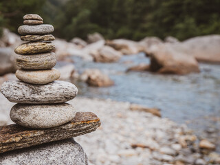 Fototapeta na wymiar Closeup shot of a carefully built rock cairn located on the tranquil river bank of a alpine river in Switzerland.