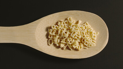 TOP VIEW: Small letter pasta appears in wooden spoon