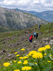 A group of tourists walks along the side of a mountain