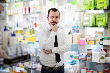 Positive man customer looking rows of drugs in drugstore
