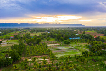 A top down aerial view of a small country town with traditional houses in Sunset besides mountain in Cambodia.
