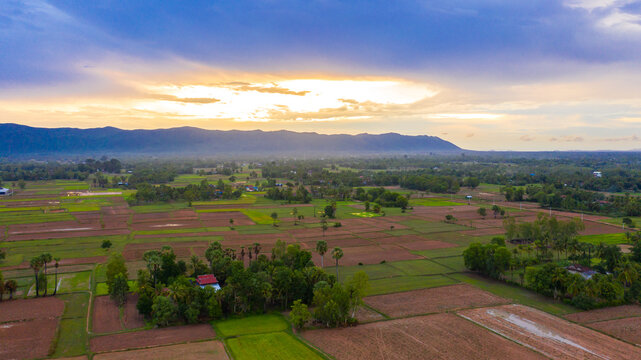 A Top Down Aerial View Of A Small Country Town With Traditional Houses In Sunset Besides Mountain In Cambodia.