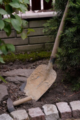 dirty shovel and hammer at the paving stone in the garden