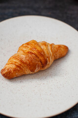 croissant on a off white plate. close up. front view.