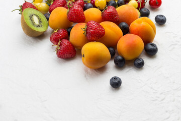 Assorted fresh berries and fruits. Apricots Kiwi Strawberry Cherry Blueberry on white background.