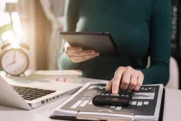 Close up male hand using calculator and tablet calculate about cost at home office.